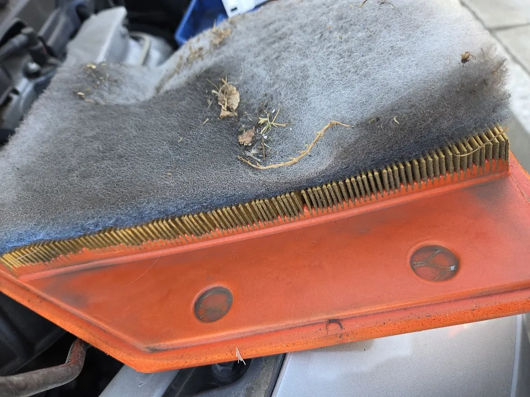 Close view of a clogged air filter pleated element covered with dirt and plant debris
