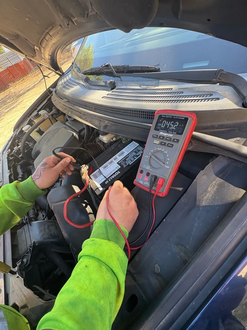 Close view of a digital multimeter connected to a car battery during a charging system test