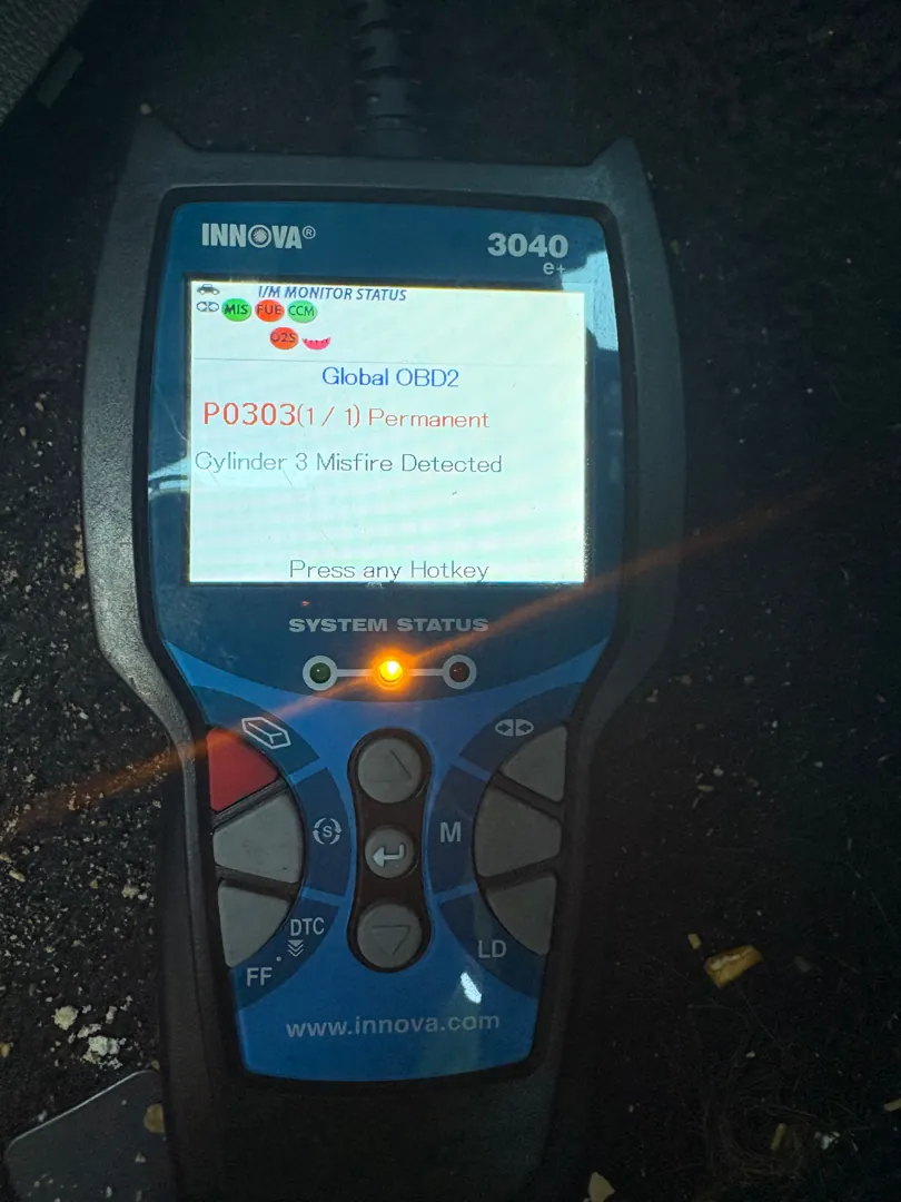 Blue handheld code reader lying on dark ground with a misfire fault code on the screen