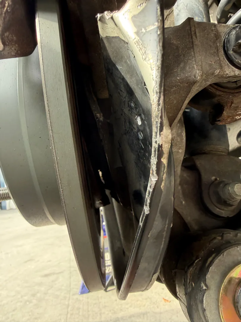 Close view of a lower control arm and bushing behind a brake rotor on a raised vehicle