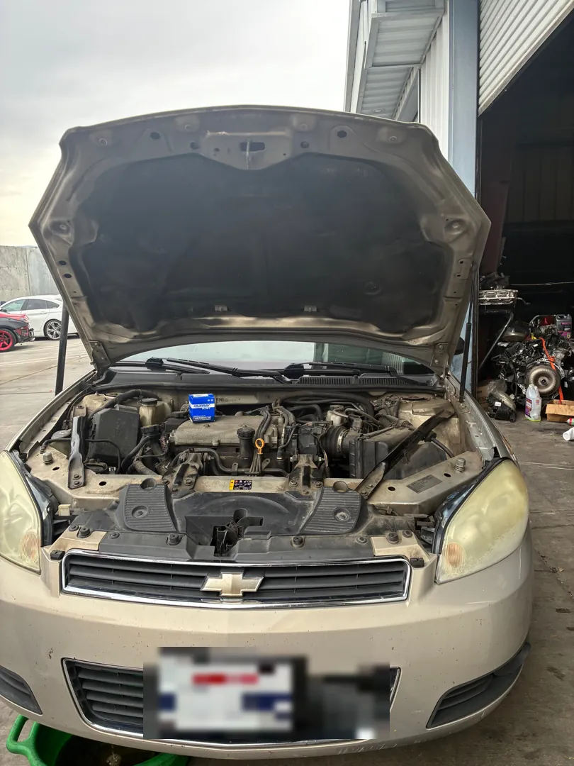 Sedan parked with the hood raised showing the radiator, coolant reservoir and engine bay during a thermostat job