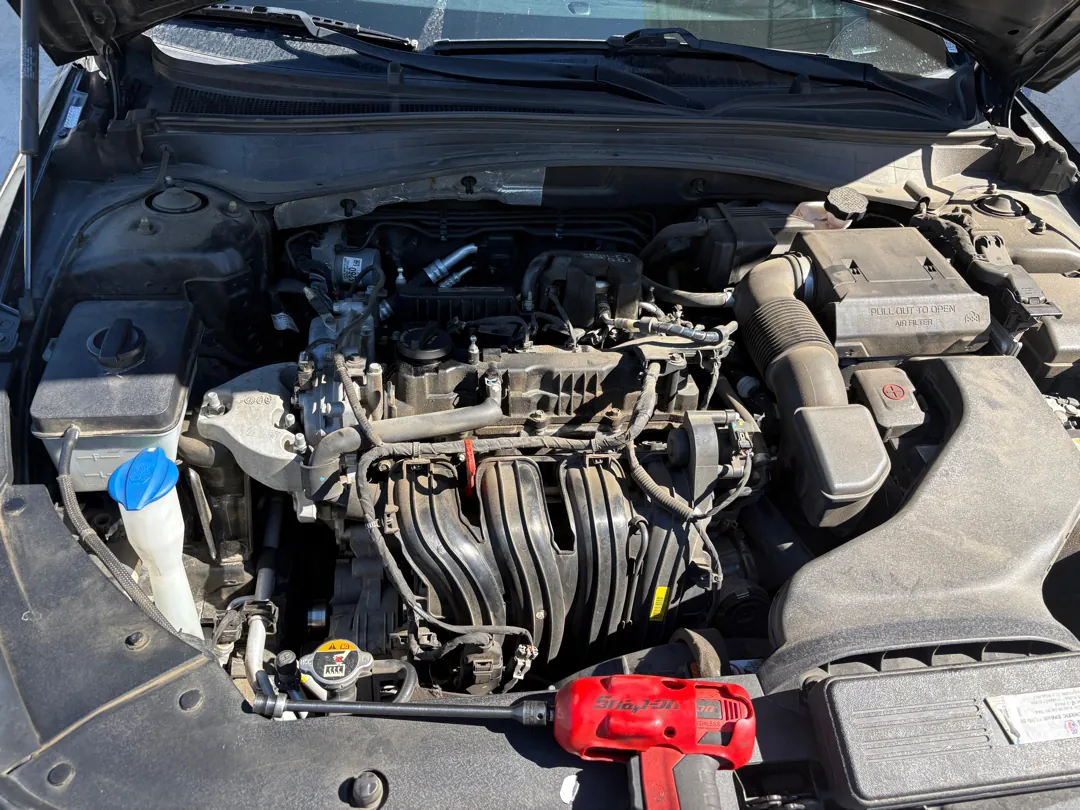 Engine bay with the ignition coil pack area exposed on top of the cylinder head during a spark plug job