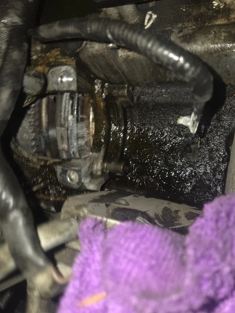 Engine bay with a protective towel laid over components during a starter replacement