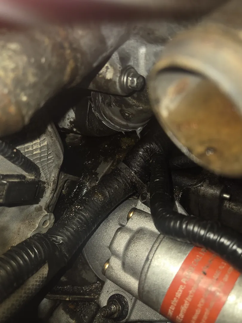 Starter motor and solenoid with its power cable visible deep in a crowded engine bay