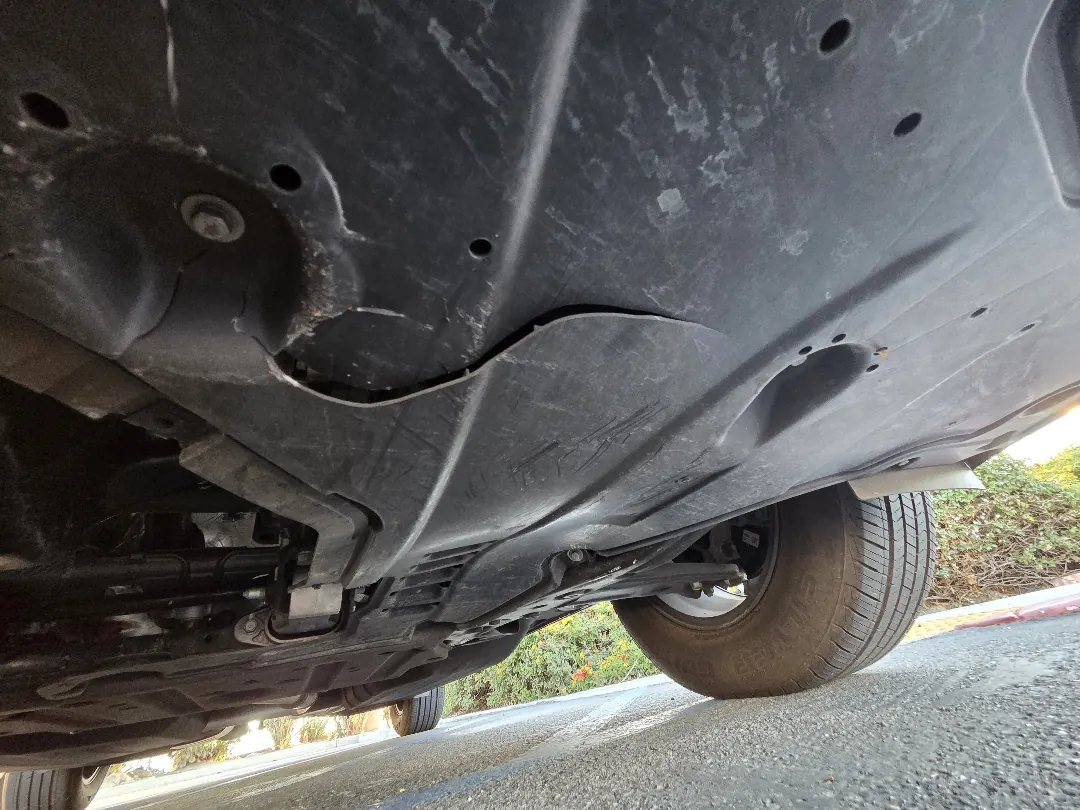 Detached engine undertray visible from beneath a vehicle with missing fasteners