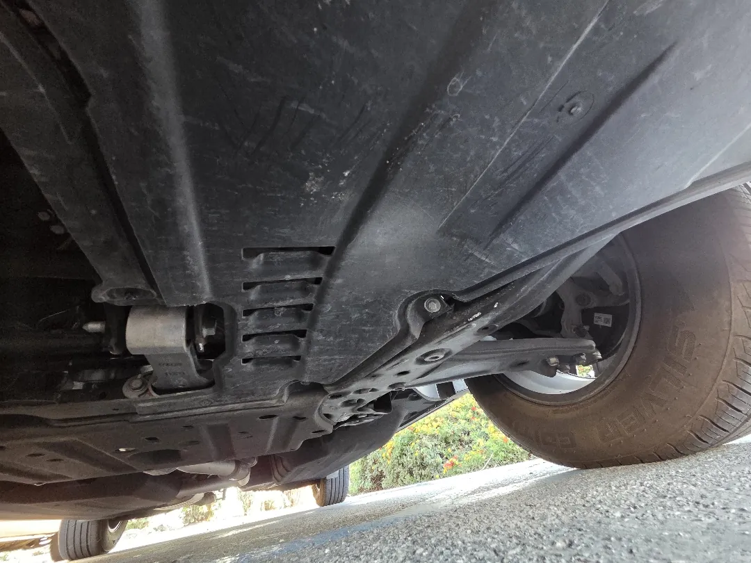 Underside of a car showing a plastic splash shield hanging loose below the engine bay